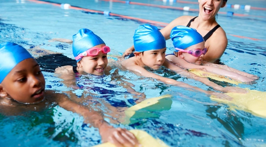 Coach teaching group of children how to swim